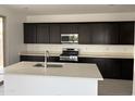 Modern kitchen with dark cabinets, stainless steel appliances, and center island at 18061 W Lupine Ave, Goodyear, AZ 85338
