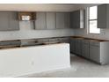 Bright kitchen features abundant gray cabinetry, neutral paint, and plenty of natural light at 20756 N 224Th Ave, Surprise, AZ 85387