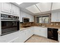 Bright kitchen with white cabinets, granite countertops, and modern appliances under a skylight at 25230 S Berry Brook Dr, Sun Lakes, AZ 85248
