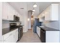 Modern kitchen with white cabinets, black appliances, and decorative backsplash at 3055 N Red Mtn # 122, Mesa, AZ 85207