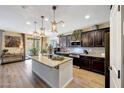 Modern kitchen features pendant lighting, an island with granite countertops, and dark wood cabinetry at 41143 W Rio Bravo Dr, Maricopa, AZ 85138