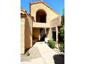 Exterior arched entry with black metal trimmed door, neutral exterior, and desert landscaping at 9115 N 101St Way, Scottsdale, AZ 85258