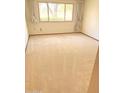 A bedroom with a large window letting in natural light and beige carpeting at 10647 W Campana Dr, Sun City, AZ 85351