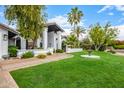 Inviting home exterior with manicured lawn, mature trees, and a circular fountain offering curb appeal at 10662 E Carol Ave, Scottsdale, AZ 85258