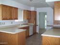 Traditional kitchen with oak cabinetry, tile flooring, white appliances, and ample counter space for food preparation at 10721 W Mission Ln, Sun City, AZ 85351
