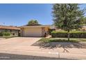 Exterior shot of a single-story home featuring a two-car garage, charming landscaping, and a well-maintained lawn at 12927 W Shadow Hills Dr, Sun City West, AZ 85375