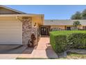 Inviting front entrance with brick accents, a pathway, mature hedges, and decorative wrought iron details, adding to the home's appeal at 12927 W Shadow Hills Dr, Sun City West, AZ 85375