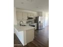 Modern kitchen features stainless steel appliances, light cabinets, quartz countertops, and wood floors at 14038 N 162Nd Ln, Surprise, AZ 85379