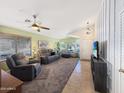 Bright living room featuring tiled floors, carpeted seating area, a ceiling fan and ample natural light through window at 16661 W Central St, Surprise, AZ 85388