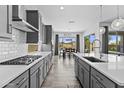 Modern kitchen with grey cabinetry, stainless steel appliances, a spacious island, and an open layout to dining area at 23097 N 95Th Dr, Peoria, AZ 85383