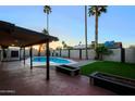 Relaxing backyard with a pristine pool, covered patio, grass, privacy wall and lush tropical landscaping at 3054 W Redfield Rd, Phoenix, AZ 85053