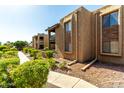 Complex exterior with green shrubs, concrete pathway, and stone accents on stucco building at 3825 E Camelback Rd # 290, Phoenix, AZ 85018
