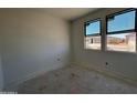 A bright, unfinished bedroom with two windows offering street views and natural light at 46869 W Old Timer Rd, Maricopa, AZ 85139