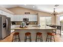 Open kitchen features granite countertops, modern stainless appliances, white cabinetry and a breakfast bar with seating at 6430 E Riverdale St, Mesa, AZ 85215