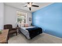 Cozy bedroom showcasing a comfortable bed, an accent wall, a ceiling fan, and a window with natural light at 7440 E Osage Ave, Mesa, AZ 85212