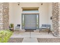 Inviting front entry with double doors, stone columns, neutral paint and a covered porch with seating at 9225 W Bajada Rd, Peoria, AZ 85383