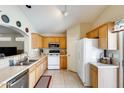 Bright kitchen featuring tile floors, double basin sink, wooden cabinets, and white appliances at 12318 W Bloomfield Rd, El Mirage, AZ 85335