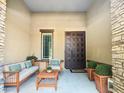 Inviting covered patio with stone pillars, comfortable seating, and a stylish steel door at 14572 W Medlock Dr, Litchfield Park, AZ 85340