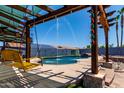 Backyard pool with a water feature, seating under pergola and desert landscaping offers relaxing outdoor living at 16210 W Durango St, Goodyear, AZ 85338