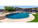 Backyard oasis featuring a large pool with a water feature, lush greenery, and a custom stone design at 16210 W Durango St, Goodyear, AZ 85338