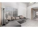 Bright living room featuring tile floors, a comfortable gray couch, and a large window with sunlight at 1950 E Kings Ave, Phoenix, AZ 85022