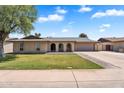 Charming single-story home featuring a manicured lawn and arched entryway under a bright blue sky at 2025 E Magdalena Dr, Tempe, AZ 85283