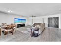 Open-concept living and dining area with gray wood floors, a large sectional couch, and a mounted TV at 2025 E Magdalena Dr, Tempe, AZ 85283