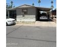 Modest single-story home featuring a covered carport and mature trees in a desert landscape at 2060 N Center St # 282, Mesa, AZ 85201