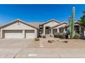 Home featuring a two-car garage and desert landscaping including cactus, bushes, and desert plants at 29816 N 51St Pl, Cave Creek, AZ 85331