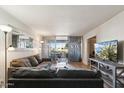Open living room with an entertainment center, plush gray sofas, an access to the patio, and a view to the bedroom at 7625 E Camelback Rd # B226, Scottsdale, AZ 85251