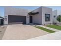 Contemporary home exterior showcases a dark garage, brick driveway, and xeriscaped yard at 7956 W Griswold Rd, Peoria, AZ 85345