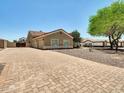 Paver driveway leading to a three-car garage, surrounded by low-maintenance landscaping and desert flora at 8031 W Morten Ave, Glendale, AZ 85303