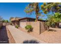 Exterior view of a house surrounded by mature trees and shrubs, complemented by a concrete block wall at 909 S Acapulco Ln # A, Tempe, AZ 85281