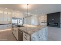 A spacious kitchen features a large granite island, white cabinets, stainless appliances, and a fireplace feature at 2005 W Lincoln Ct, Queen Creek, AZ 85144