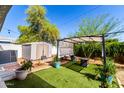 Lush backyard featuring artificial grass, a storage shed, and a shaded pergola area at 201 S Greenfield Rd # 29, Mesa, AZ 85206
