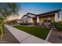 Well-maintained single-story home showcasing a tidy lawn and a covered porch with comfortable seating at 20795 W San Juan Ave, Buckeye, AZ 85396