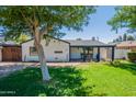 Inviting single-story home with a well-manicured lawn, mature shade trees, and a covered porch at 317 E Orange Dr, Phoenix, AZ 85012