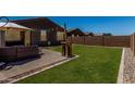Spacious backyard features a well-maintained lawn, patio with seating, string lights, and a view of neighboring houses at 40380 W Jenna Ln, Maricopa, AZ 85138