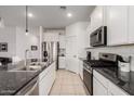Modern kitchen boasts white cabinets, stainless steel appliances, granite countertops, and a stylish tile backsplash at 40380 W Jenna Ln, Maricopa, AZ 85138