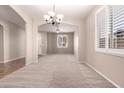 Open-concept living room with neutral walls, tile flooring, lots of natural light and carpet at 43670 W Mcclelland Ct, Maricopa, AZ 85138