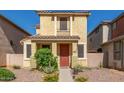 Inviting two-story home featuring a cozy porch, desert landscaping and a red entry door at 5 N 87Th Ln, Tolleson, AZ 85353