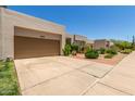 Exterior of a desert-style home featuring a spacious driveway leading to an attached two-car garage at 9389 N 87Th Way, Scottsdale, AZ 85258