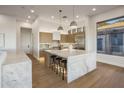 Modern kitchen with large marble island, wood cabinets, stainless steel appliances, pendant lights, and wood floor at 13631 E Windrose Dr, Scottsdale, AZ 85259
