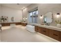 Luxury bathroom featuring dual vanities, a modern soaking tub, and a bright window at 13631 E Windrose Dr, Scottsdale, AZ 85259