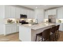 Modern kitchen featuring white cabinets, stainless steel appliances, and an island with seating at 15357 W Cottontail Ln, Surprise, AZ 85387