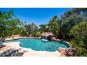 Beautiful pool with rock waterfall feature surrounded by lush landscaping and tropical plants at 2101 S 167Th Dr, Goodyear, AZ 85338