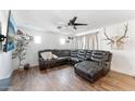 Bright living room featuring dark wood-look floors, a ceiling fan and a comfortable reclining sectional at 3508 E Gelding Dr, Phoenix, AZ 85032