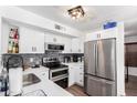 This modern kitchen features white cabinets, stainless steel appliances, and a stone tile backsplash at 3829 W Camino Del Rio --, Glendale, AZ 85310
