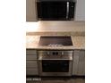 Close-up of stainless steel oven and induction cooktop installed below the microwave and granite countertop at 5720 S 21St Ter, Phoenix, AZ 85040