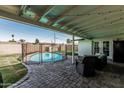 A fenced, in-ground pool is surrounded by brick pavers and outdoor seating under a covered patio at 591 N Cheri Lynn Dr, Chandler, AZ 85225